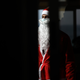 Man dressed as Santa stands in the shadows